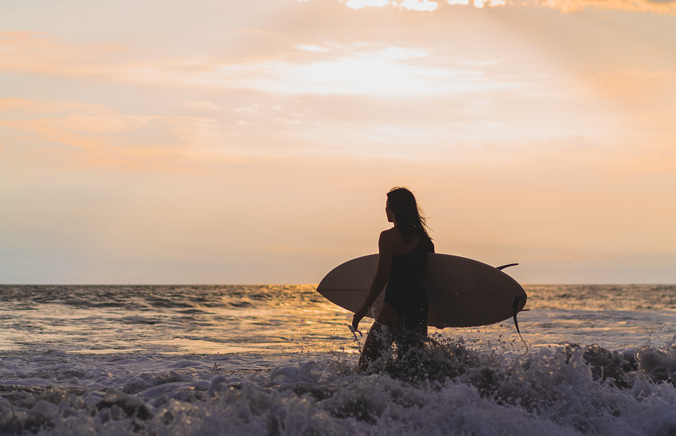 Surf & yoga getaway Person entering the sea with a surfboard
