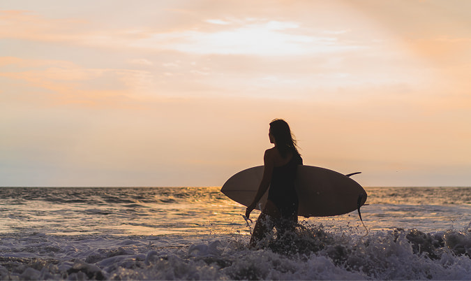 Surf & yoga getaway Person entering the sea with a surfboard