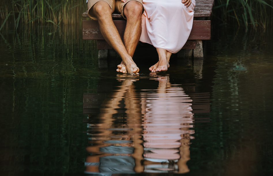 Romantic getaway Legs of a couple sitting on a jetty