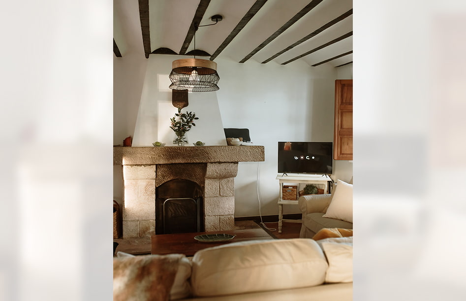 Rural House 4 Fireplace in front of the sofa, next to a small TV set