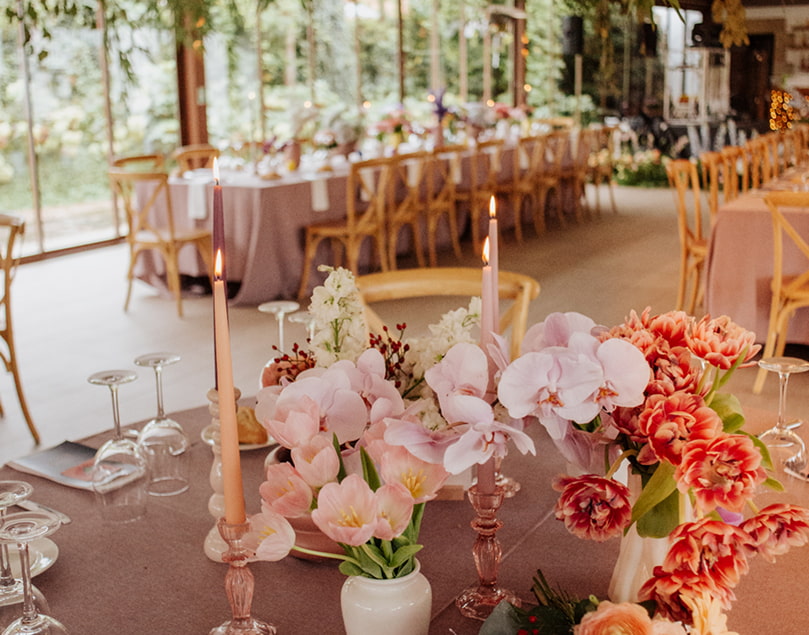 Bodas & Eventos 2 Primer plano de un centro de mesas, con el salón de bodas al fondo